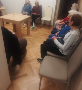 Református Istentiszteletet hallgatnak az idősek a közös helyiségben.